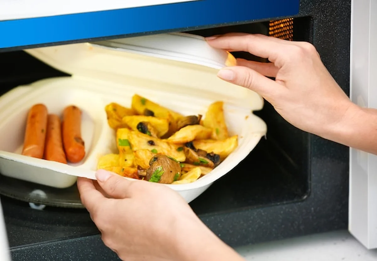 Kobieta wkładająca pojemnik do kuchenki mikrofalowej