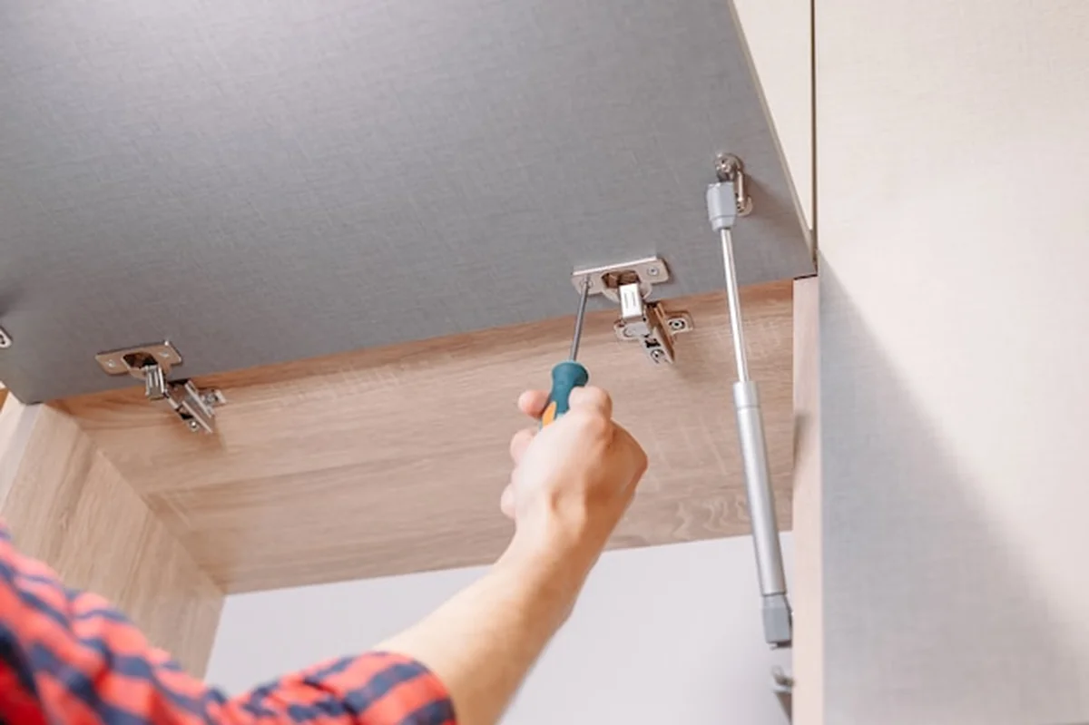 Mężczyzna montuje nowe meble śrubokrętem