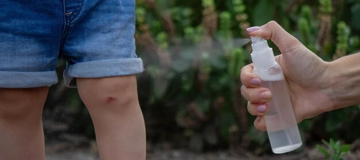 Matka nakłada aerozol z owadami na ciało dziecka