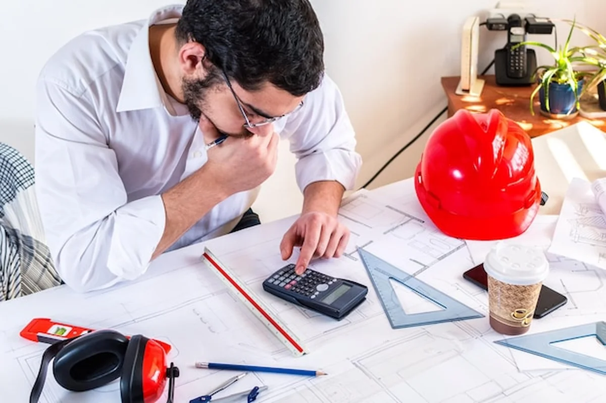 Młody inżynier architekt robi obliczenia na biurku