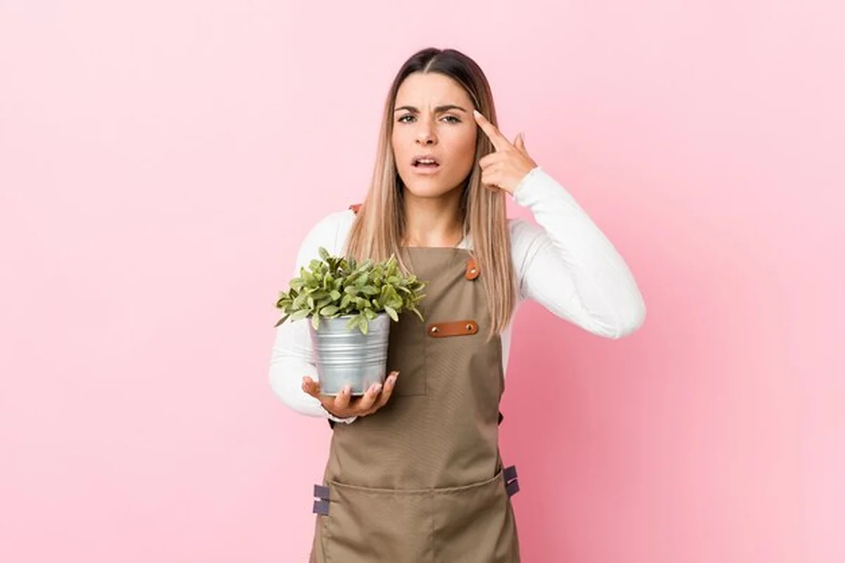 Młoda ogrodniczka trzymająca rośliny z gestem rozczarowania