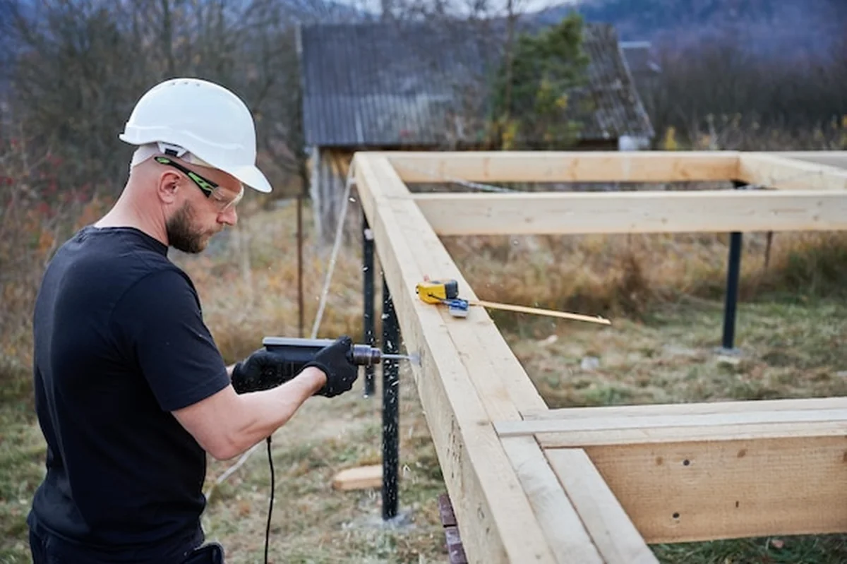 Pracownik budujący drewniany dom na fundamencie