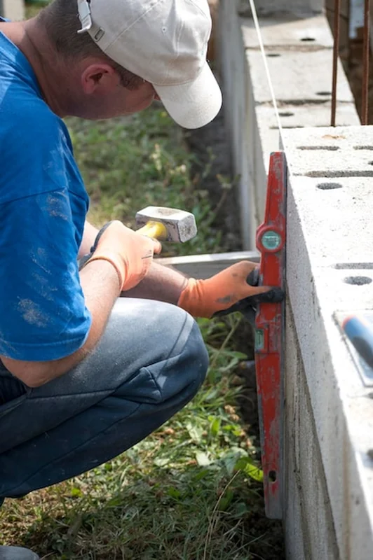 Murarz w rękawicy rozprowadza beton na budowie