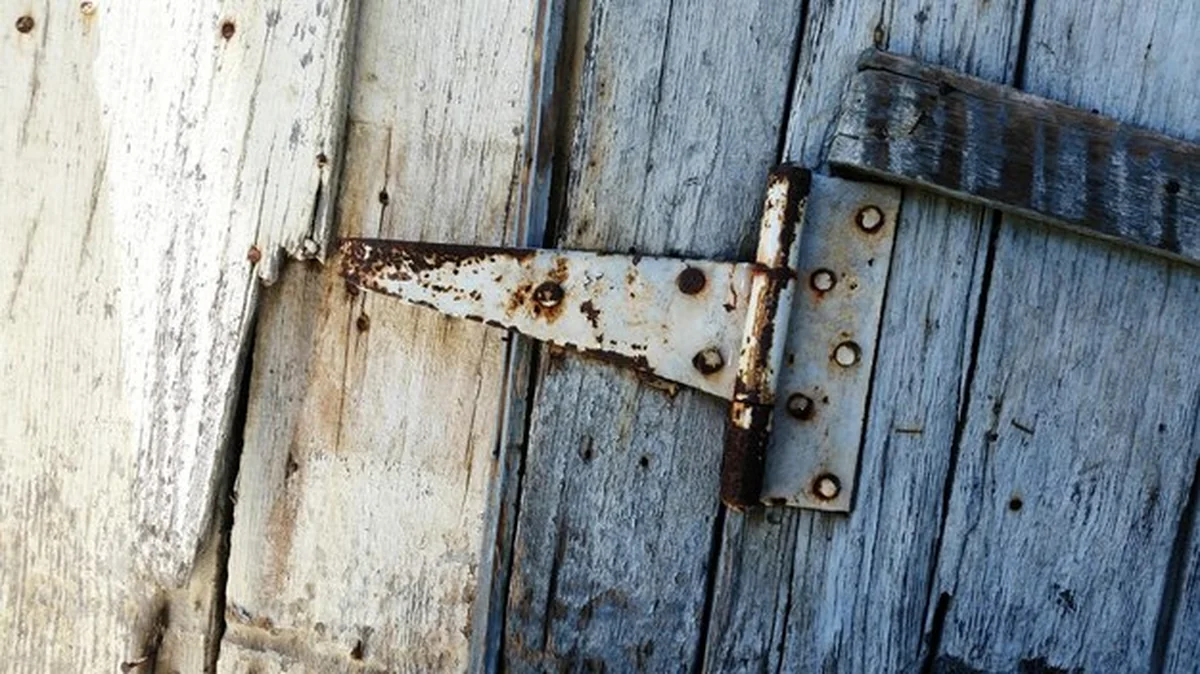 Zardzewiały zawias na drewnianych drzwiach