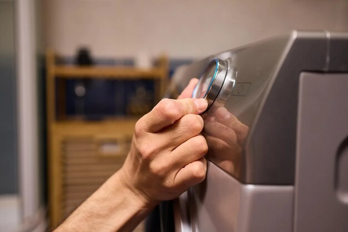 Osoba obsługująca panel sterowania nowoczesną pralką