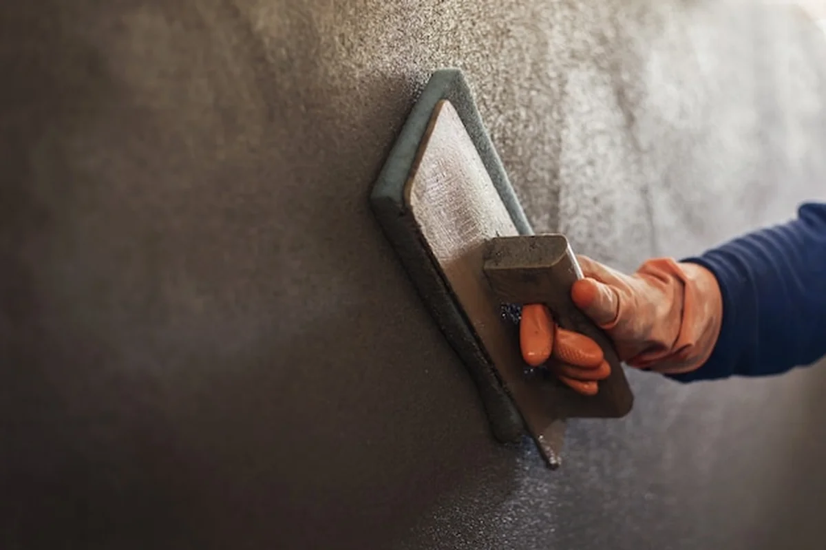Tynkowanie betonu narzędziami tynkarskimi przez pracownika przemysłowego