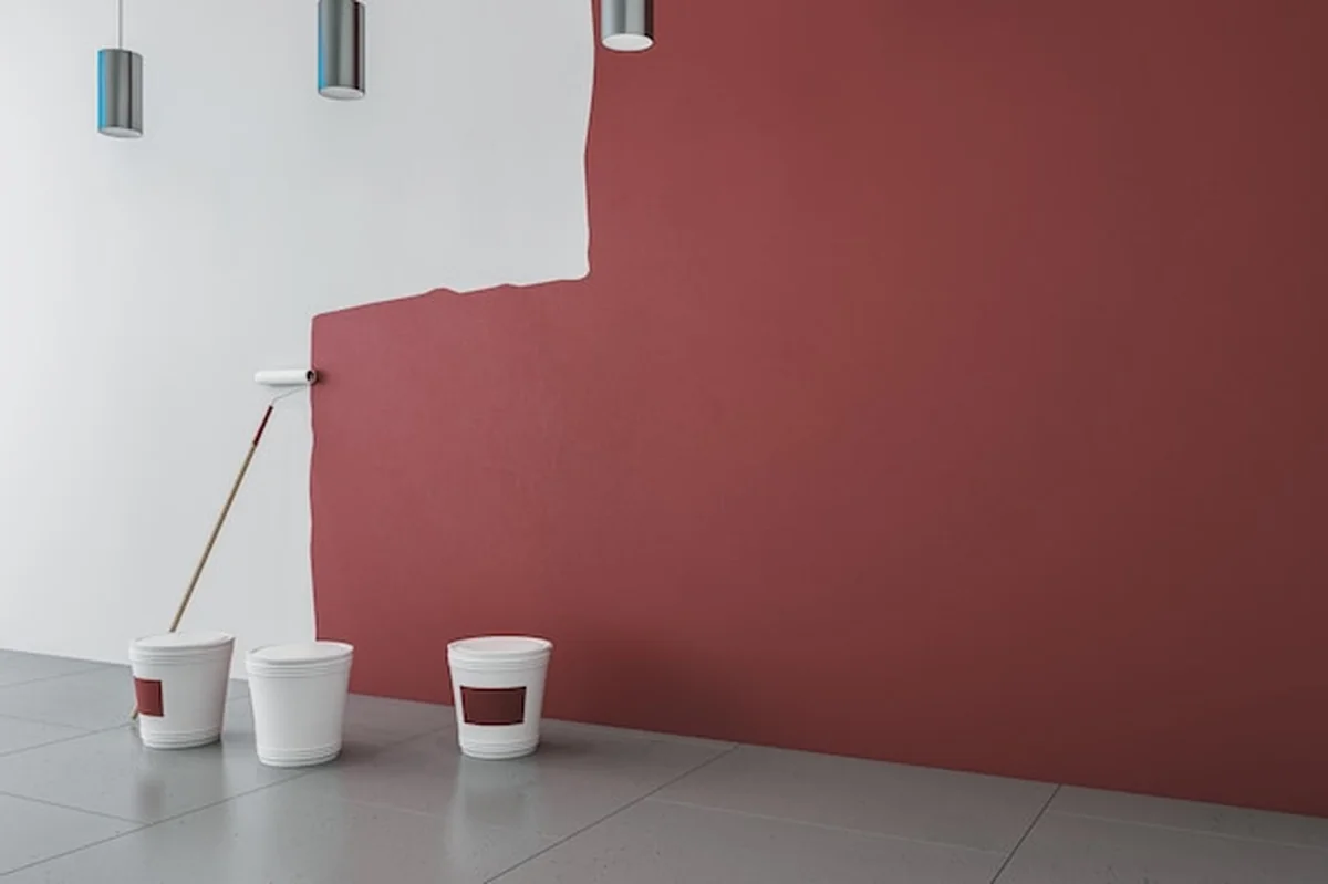 Wnętrze z czerwoną farbą na białej ścianie, narzędzia do malowania, lampy drabinkowe i betonowa podłoga