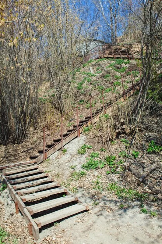 Strome zbocze wzgórza z drewnianymi schodami i zardzewiałymi metalowymi poręczami